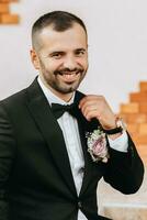 Handsome bearded man groom in black suit and black bow tie standing outdoors. Wedding portrait. A man in a classic suit photo