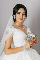 the bride holds a boutonniere in her hands. wedding flowers A luxurious woman is enjoying her day. Luxury wedding dress. Professional makeup photo