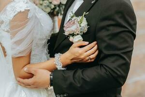 Portrait of a happy newlywed wife and husband hugging outdoors and enjoying a wedding bouquet of white roses. Sincere feelings of two young people. The concept of true love. photo