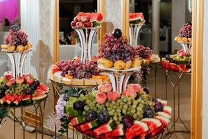 Wedding decorations. Reception. Buffet. Fruits and cheese on plates with bread in boxes. Food bar decorated by flowers and lanters photo