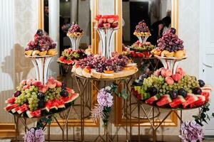 Wedding decorations. Reception. Buffet. Fruits and cheese on plates with bread in boxes. Food bar decorated by flowers and lanters photo