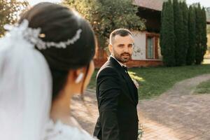 The groom leads the bride by the hand during sunset. photo