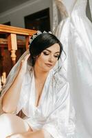 un contento novia es preparando para su lujo Boda en un hotel habitación, participación su hermosa vestido. retrato de un mujer con profesional pelo y maquillaje y un sonrisa en un vendaje vestido foto