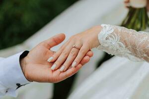 Close-up of groom's hand holding bride's wirst tender photo