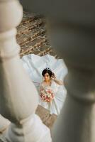 young beautiful bride in wedding dress and crown on head lying on stone steps, fashion shot under harsh sunlight. The photo is taken from above