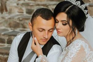 a beautiful bride in a chic wedding dress and an elegant groom stand on ancient steps in the park photo