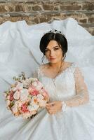 a beautiful bride in a chic wedding dress stands on ancient steps in the park photo