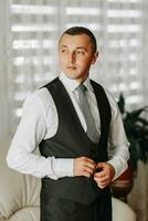 a businessman is getting dressed in preparation for a meeting. The groom is preparing for the wedding. The man is wearing a white shirt. Stylish groom photo