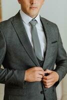 the man fastens the buttons on his jacket. The groom is preparing for the wedding ceremony. Detailed close-up photo of hands