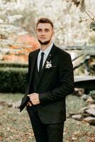 portrait of the groom in a black suit with a beard, looking into the lens photo