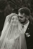 de cerca Disparo de un elegante morena novia en un blanco vestir posando debajo un velo de cerca. novia retrato, Boda maquillaje y peinado, nupcial moda. hermosa novia en un velo foto