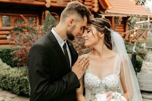 gorgeous elegant luxurious bride with veil blowing in the wind. and a stylish groom kiss outdoors near tall autumn trees photo