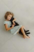 A happy child is lying on the veranda with his favorite black cat. A little girl rests on the floor of the veranda on a sunny summer day. A happy and carefree childhood. photo