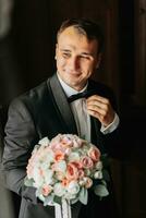 preparación para el Mañana de el novia y novio. retrato foto de un elegante hombre consiguiendo vestido para un Boda celebracion. el acicalar, vestido en un blanco camisa, arco Corbata y chaqueta