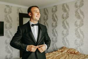 Preparation for the morning of the bride and groom. portrait photo of an elegant man getting dressed for a wedding celebration. The groom, dressed in a white shirt and bow tie