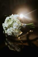 accesorios en el del novio Boda día. un ramo de flores de blanco rosas en un oscuro antecedentes con iluminar desde el fondo. de los hombres Moda foto