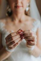 The bride is holding a gold ring in her hands, close-up. Morning of the bride. Wedding day. Open shoulders. Sexy girl photo