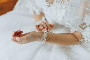 wedding dress with sleeves. The bride is preparing for the wedding, fastens the buttons on the sleeve of the dress photo