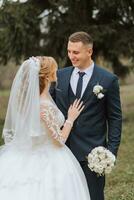 portrait of an elegant wedding couple tenderly embracing in a forest or park. luxury bride and groom embracing. romantic sensual moment photo