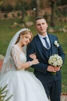 portrait of an elegant wedding couple tenderly embracing in a forest or park. luxury bride and groom embracing. romantic sensual moment photo