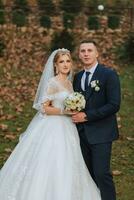 retrato de un elegante Boda Pareja tiernamente abrazando en un bosque o parque. lujo novia y novio abrazando romántico sensual momento foto