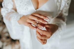 The bride is holding a gold ring in her hands, close-up. Morning of the bride. Wedding day. Open shoulders. Sexy girl photo