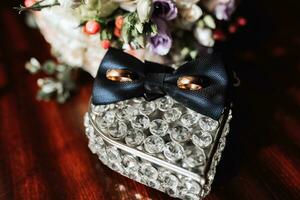 Groom's accessories in the morning. Gold wedding rings, black shirt cufflinks, bow tie photo