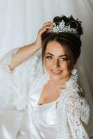 Gorgeous bride portrait in her robe wearing tiara. Beautiful bridal makeup and hairstyle and hair accessories. Bride to be smiling portrait photo