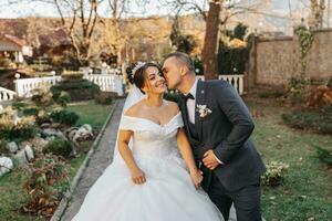 The groom holds the bride's hand and walks. of the bride against the background of the sun's rays, the park and the forest. photo