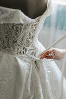 Close-up photo of a beautiful bride untying her wedding dress on a mannequin and getting ready to put it on