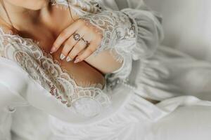 An incredibly beautiful bride poses for a photographer in the morning in a satin robe. Dress with open female breasts close-up. photo