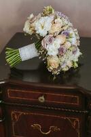 Accessories on the groom's wedding day. A bouquet of different flowers and roses on the table in the room. Men's fashion photo