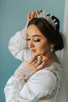 A wonderful portrait of a bride in a robe with a tiara on her head. Beautiful wedding makeup, hairstyle and hair accessories. Bride smiling, portrait photo