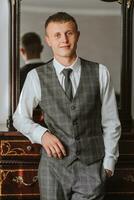 A stylish young man is wearing a suit and tie. Business style. Fashionable image. The groom is preparing for the wedding. A sexy man is standing and looking into the camera lens photo