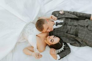 portrait of the bride and groom lying on the grass and kissing. An incredibly beautiful bride. Stylish groom in a suit photo