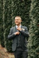 hermoso novio en traje y Corbata en pie al aire libre en parque. Boda retrato. un hombre en un clásico traje foto