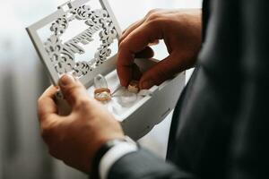 dorado Boda anillos en un regalo caja, en el manos de el acicalar, de cerca foto