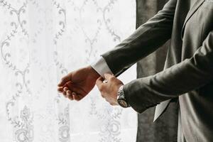 Male portrait. Photo session by the window. Groom's collection. The groom puts on a jacket. Wedding photo