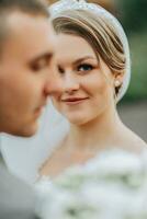 Stylish bride and groom tenderly embrace and kiss. Beautiful bride with modern bouquet embracing stylish groom in autumn park. Sensual romantic moment. Wedding. Stylish and beautiful. photo