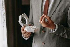 Golden wedding rings in a gift box, in the hands of the groom, close-up photo