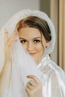 The bride in the room in a silk robe. The bride is preparing for the wedding photo