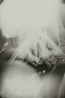 beautiful bare legs of the bride under veil lying on the bed. Black and white photo
