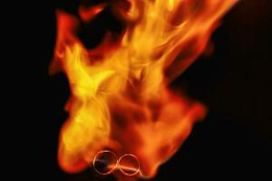 two wedding rings in the flames of fire. Wedding. Traditions. Fiery flame on a dark background photo