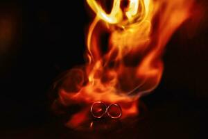 two wedding rings in the flames of fire. Wedding. Traditions. Fiery flame on a dark background photo