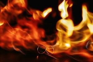 two wedding rings in a flame of fire on a dark background. Wedding. Traditions. Fire element photo