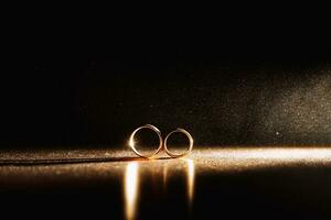 dos Boda anillos en infinito firmar con espumoso ligero neblina. amor concepto en negro antecedentes foto