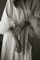 Morning of the bride, woman wearing a white silk robe, close-up photo of female hands. Black and white photo