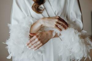 Morning of the bride, woman wearing a white silk robe, close-up photo of female hands.