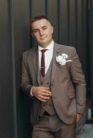 Portrait of an adult male groom in a stylish suit of brown shades outdoors. photo