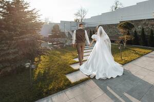 the bride and groom walk after the wedding ceremony in a beautiful location at sunset. Happy bride in a long wedding dress. Wedding day. A warm autumn wedding. photo